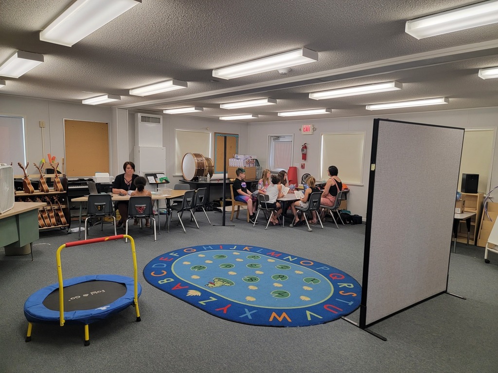 students and teachers sitting at two tables learning in a classroom